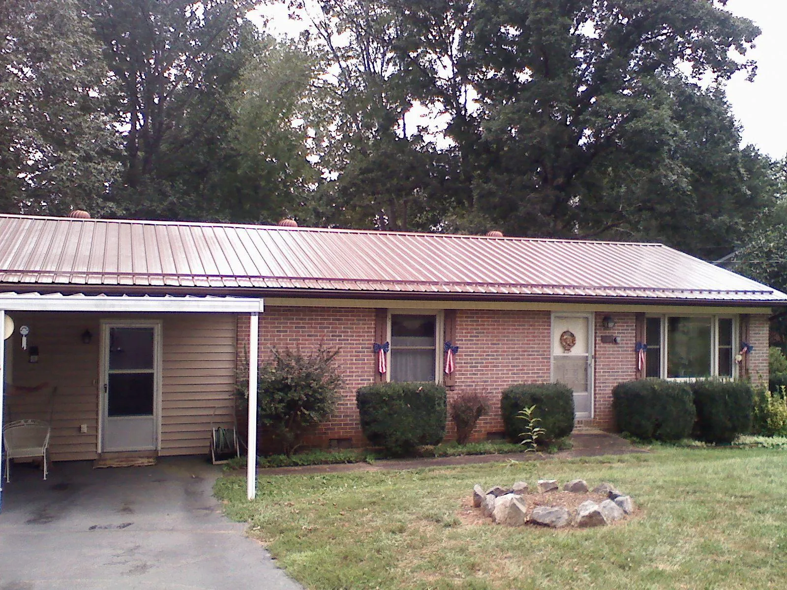 Bronze metal roof and carport on a brick ranch home — Roof Repair work by our crew in Russell